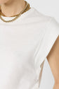 A person wearing a sleeveless white top and layered gold necklaces, shown from the shoulders up against a plain background.