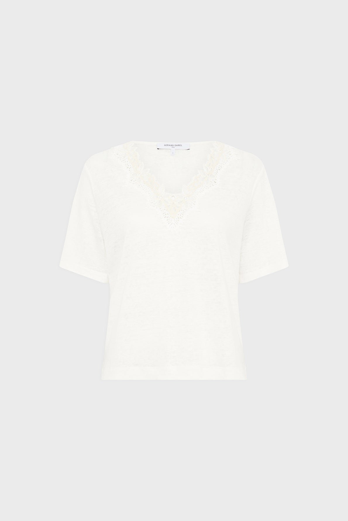 White short-sleeve col V tee-shirt lin with delicate lace trim and subtle broderie florale around the neckline, displayed on a plain light gray background.