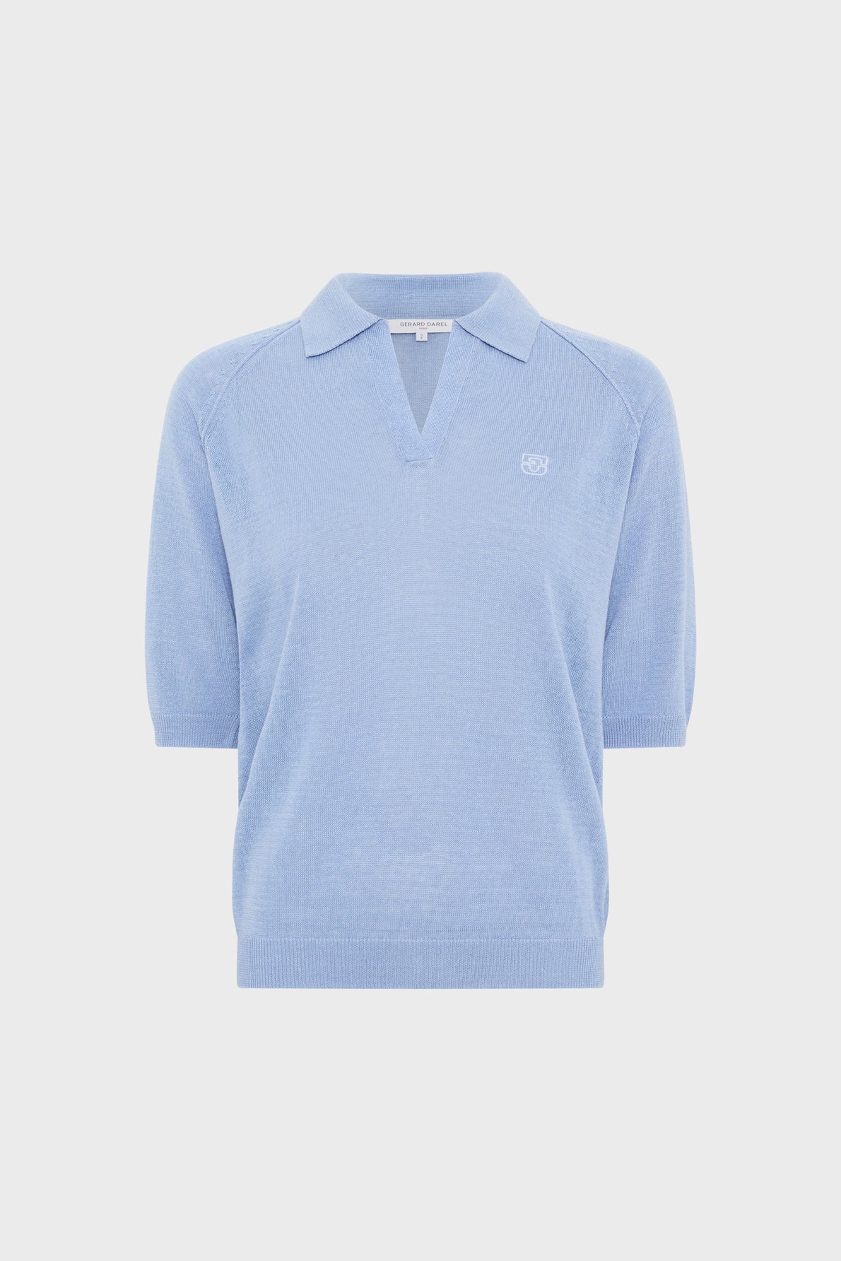 Light blue short-sleeve polo en lin with a collar, V-neckline (col polo ouvert), ribbed hem and cuffs, and a small embroidered logo on the left chest, displayed on a plain white background.