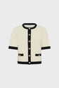 Short-sleeved cream gilet en maille with black trim, gold buttons down the front, and two front pockets, displayed on a plain white background.