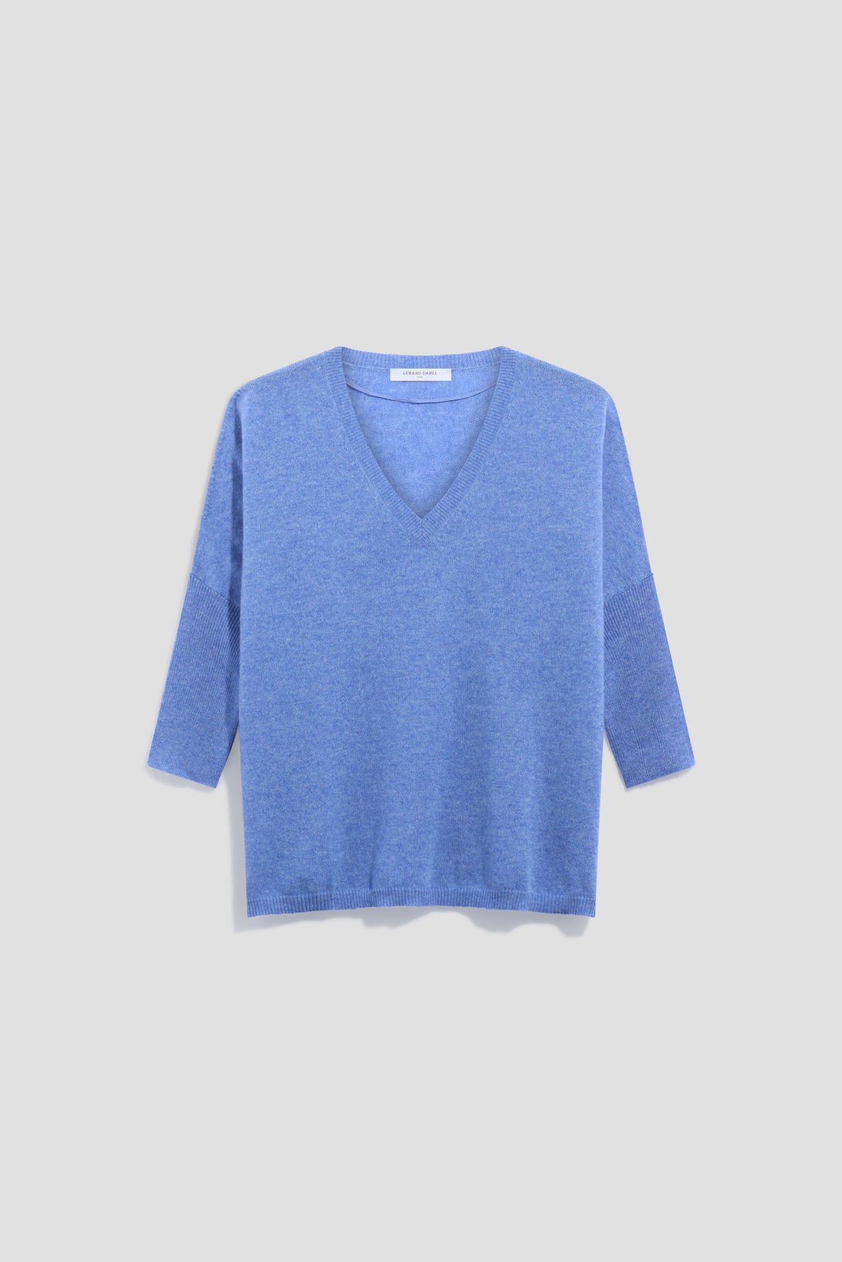 A light blue, long-sleeve cachemire pull femme with a col V is displayed on a plain, pale gray background. The sweater has a relaxed fit and ribbed cuffs and hem.