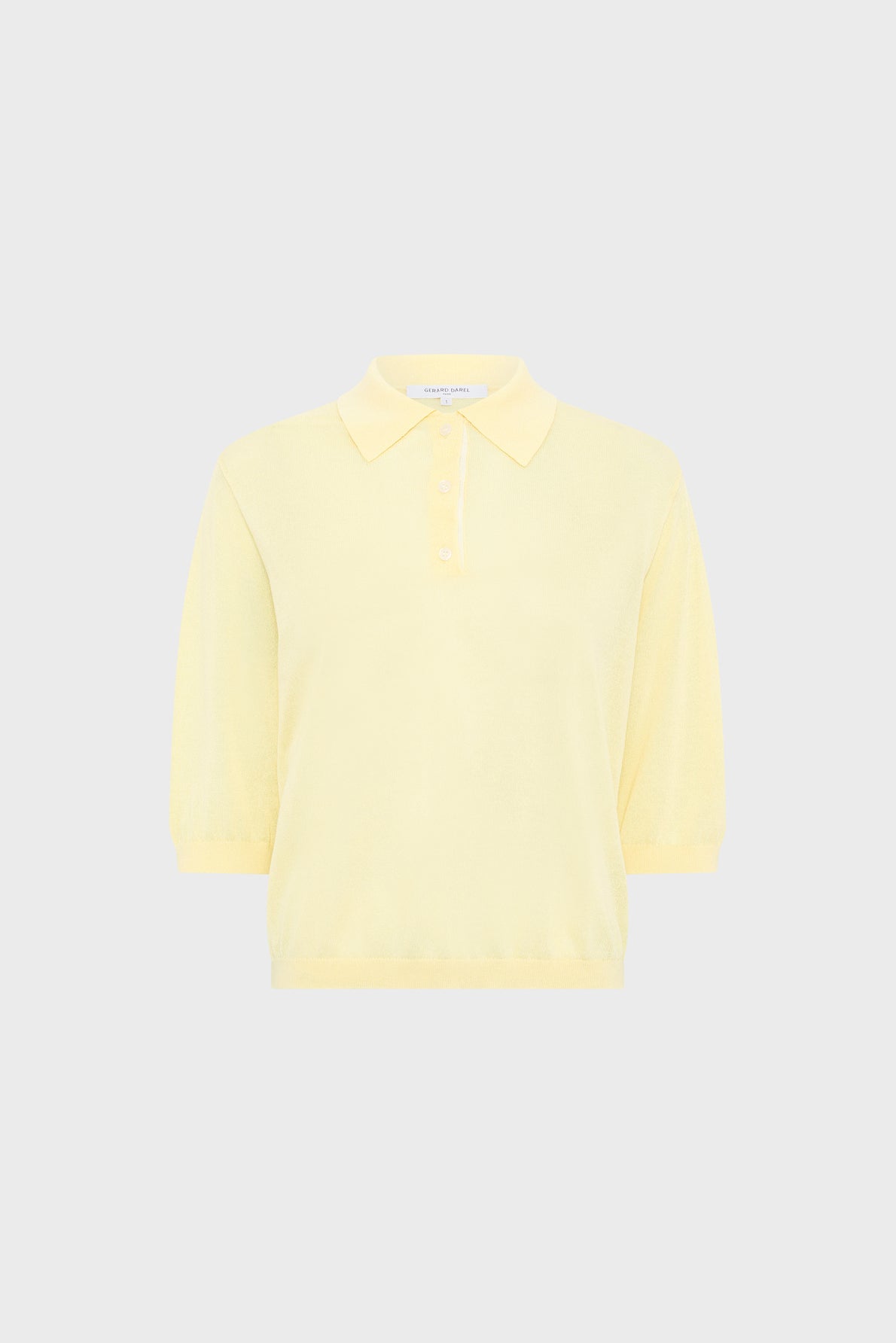 Light yellow short-sleeve polo shirt with a collar and three buttons, displayed against a plain light gray background.