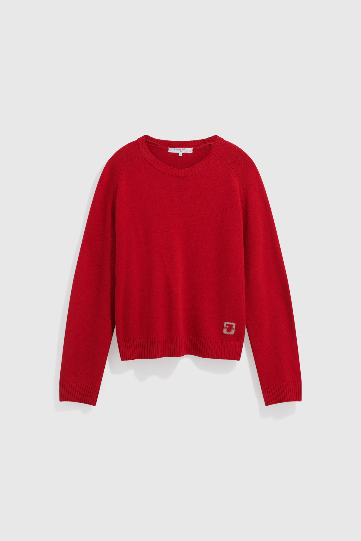 Red long-sleeve crewneck sweater with a ribbed hem and cuffs, displayed on a plain white background. This stylish pull col rond features a small square logo near the bottom hem on the left side.