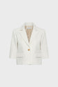 Cropped white veste courte with a subtle motif jacquard pattern, notched lapels, three-quarter sleeves, two front flap pockets, and a single gold button closure, displayed on a plain light background.