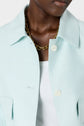 A person wearing a light blue veste à col chemise over a white ribbed top and a gold chain necklace. The image is cropped to show only the lower face, neck, and upper torso.