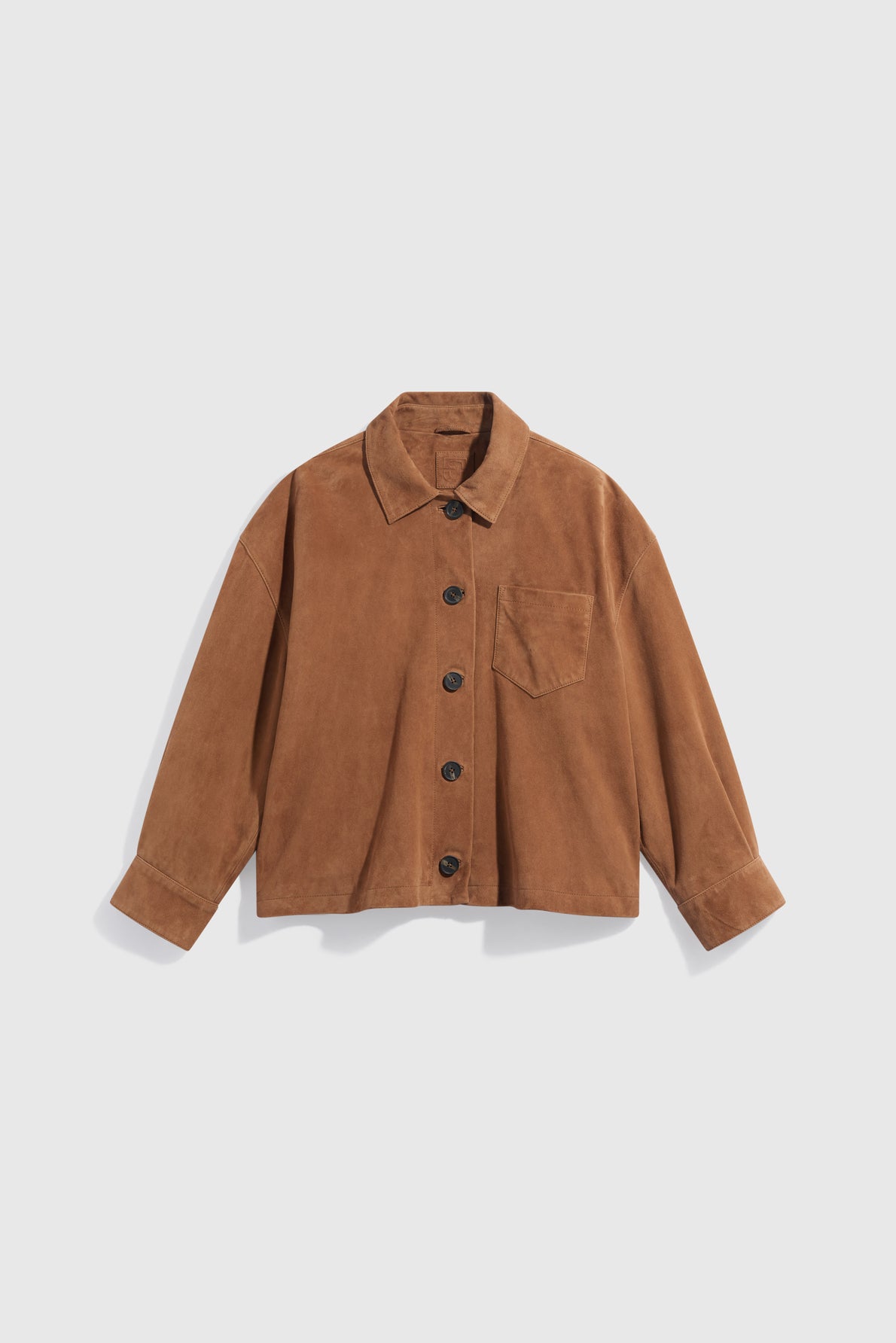 Brown suede button-up jacket with a collar, long sleeves, black buttons, and a single chest pocket, displayed on a plain white background. This veste en cuir velours combines timeless style with modern versatility, making it an ideal piece for layering as a veste surchemise.