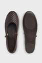 A pair of dark brown cuir tressé Mary Jane flats, shown from the top and bottom views, with a small gold buckle bride à boucle on the strap and a textured rubber sole.