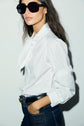 Chemise Louka blanche en popeline avec col cravate portée avec un jean et une ceinture noire