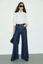 Chemise a col cravate en popeline LOUKA blanche portee avec un jean large bleu fonce et une ceinture noire