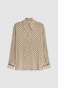 Beige long-sleeve button-up chemise fluide with a repeating black geometric motif imprimé and black trim on the cuffs, displayed on a plain white background.