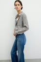A person stands against a plain background wearing a chemise à rayures au motif rayé and blue jeans, looking toward the camera with a neutral expression. The matière fluide of the shirt adds a subtle elegance to the overall look.
