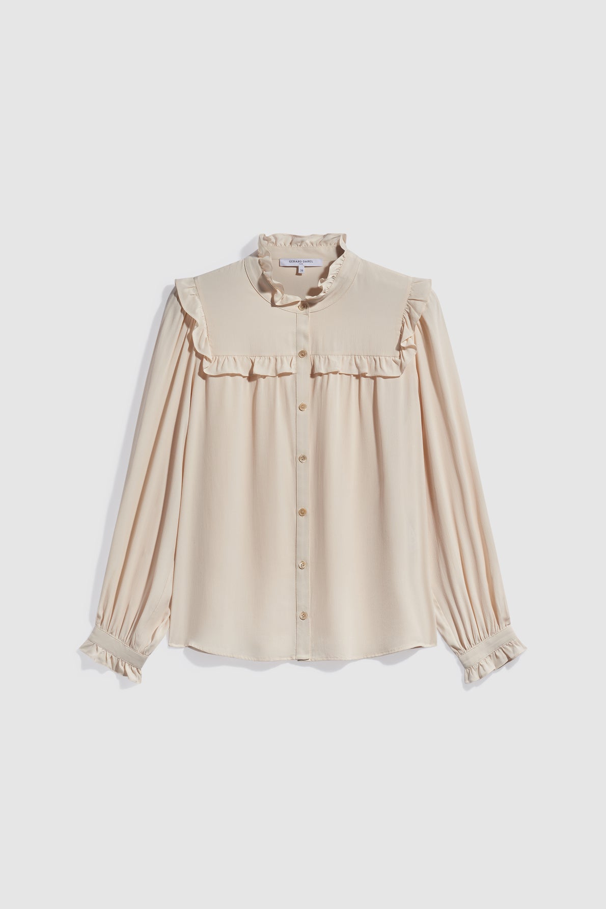 Cream-colored long-sleeve blouse with ruffled collar, shoulders, and cuffs, reminiscent of a chic chemise à volants. Button-down front with a loose fit and soft, lightweight fabric in the style of a classic chemise soie, displayed on a plain white background.