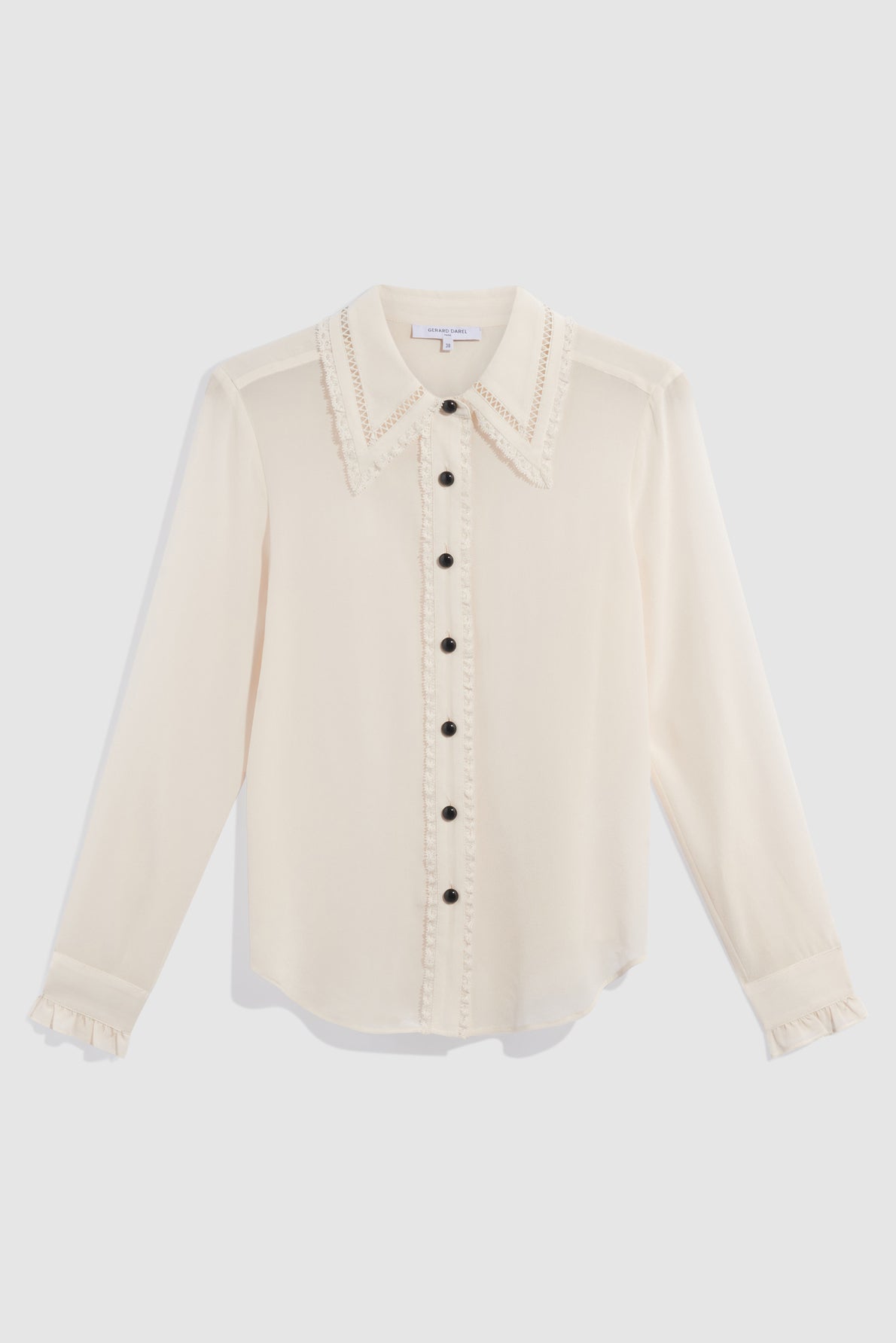 Long-sleeve cream chemisier femme with black buttons, delicate dentelle trim on the collar and down the button placket, and ruffled cuffs, displayed on a white background.