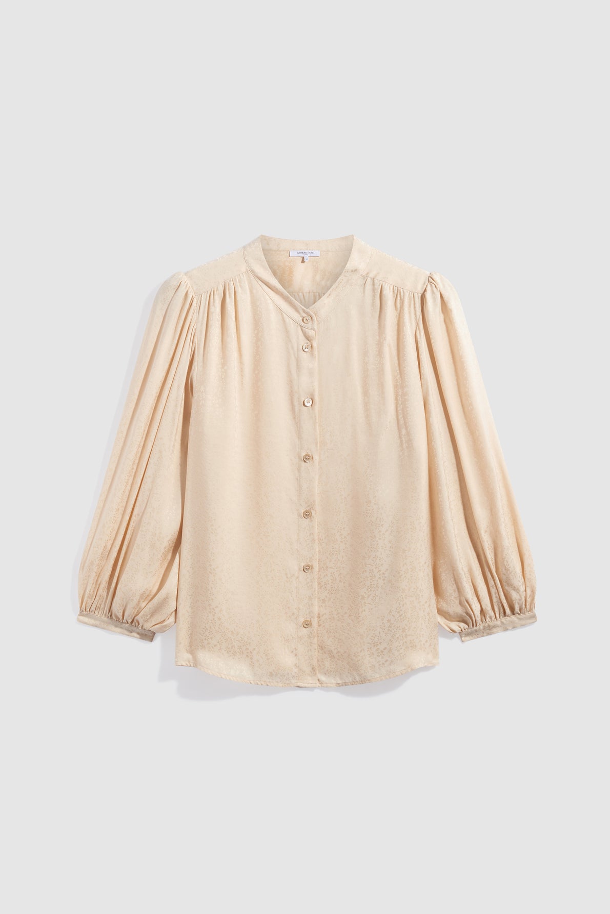 Cream-colored, long-sleeve chemise jacquard blouse with a subtle sheen, button-down front, round neckline, and gathered shoulders and cuffs, displayed against a plain light gray background.