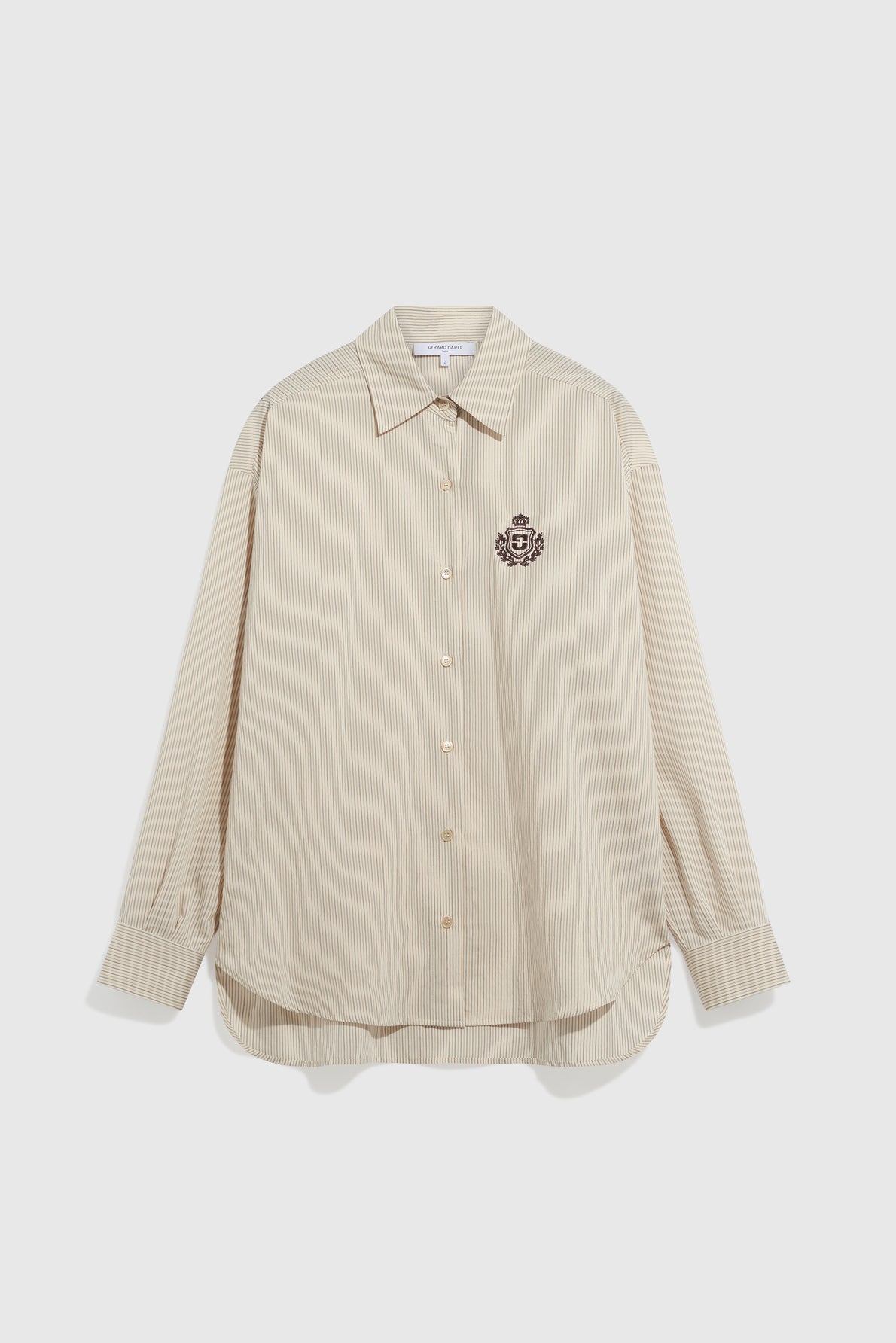Beige, long-sleeve, button-up chemise preppy with thin vertical stripes and an embroidered dark crest on the left chest. This chemise rayée features a pointed collar and a rounded hem for a classic, polished look—a timeless chemise femme for any wardrobe.