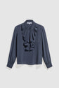 Dark blue long-sleeve blouse with a round neckline, front button closure, and layered ruffles down the front. This elegant blouse en soie features sleeves gathered at the cuffs and is displayed on a plain white background.