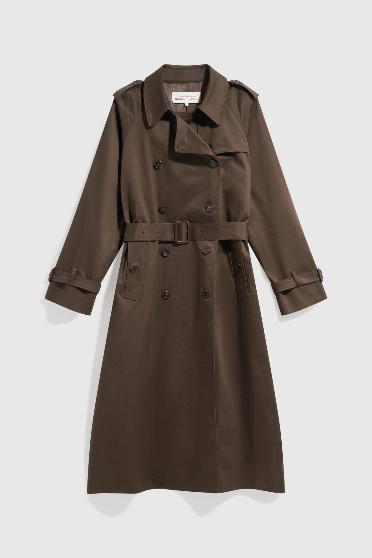 Long dark brown trench coat with a belt, double-breasted buttons, epaulets on the shoulders, and adjustable straps on the sleeves, this élégant manteau femme is displayed on a light background.