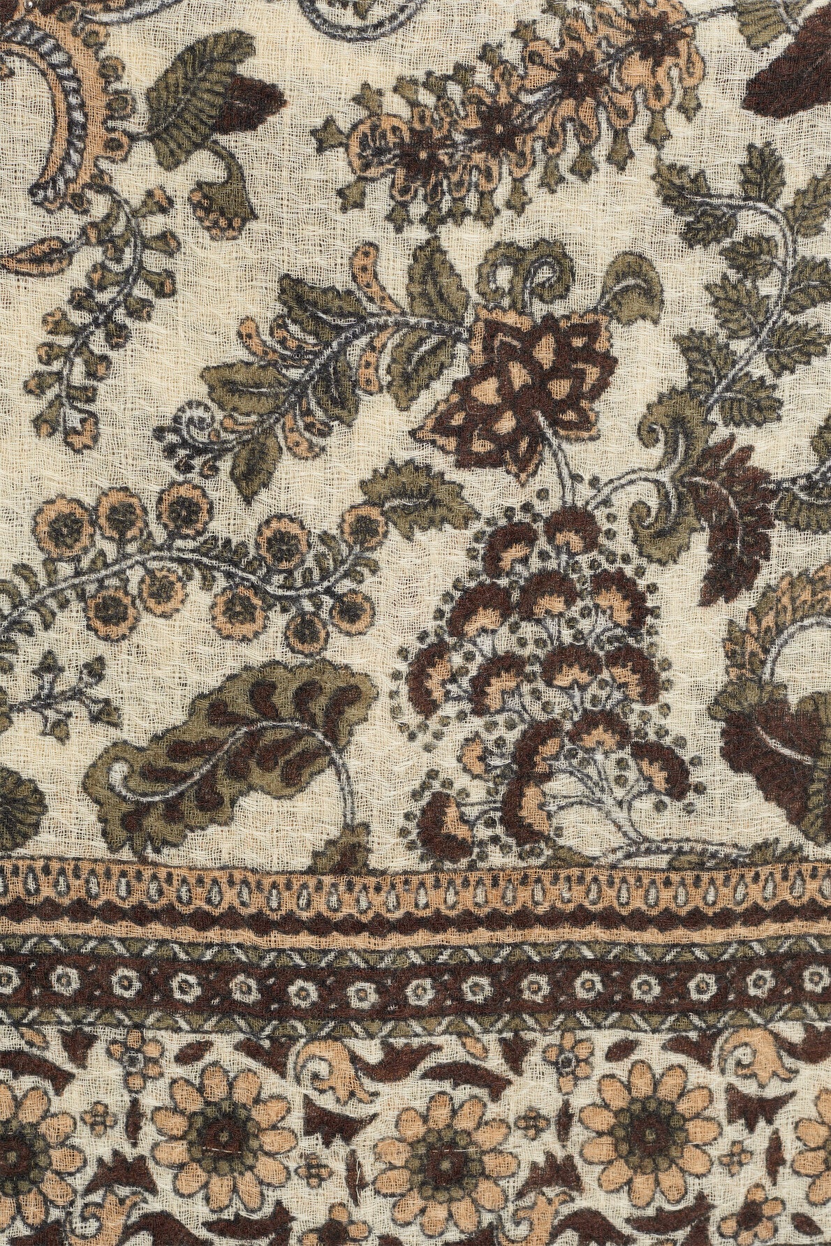 Intricate floral and leaf patterns in earthy tones are printed on a light beige fabric, creating an elegant écharpe imprimée crafted from a luxurious blend of laine et soie, with a detailed border featuring stylized flowers and vines at the bottom.