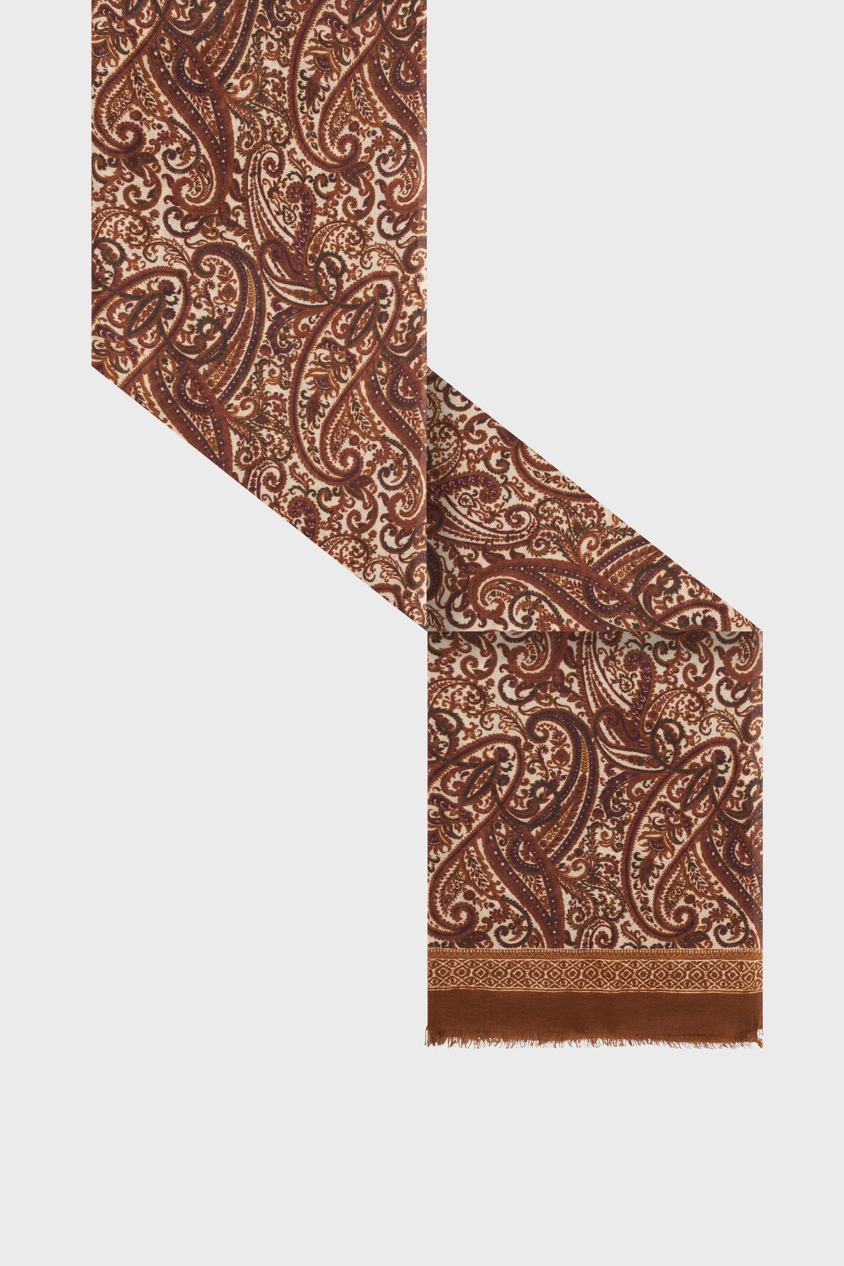 A brown and beige écharpe laine soie with an intricate imprimé cachemire pattern is displayed diagonally on a white background. The edge of the écharpe brune features a solid brown border with short fringe.