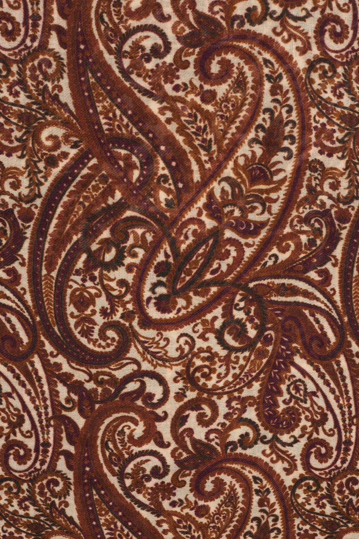 Close-up of a fabric featuring an intricate imprimé cachemire pattern in shades of brown, burgundy, and black on a cream background, with swirling floral and leaf motifs.
