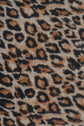 Close-up of an écharpe léopard in soft laine cachemire, featuring an imprimé léopard pattern of irregular black spots and brown patches on a beige background.