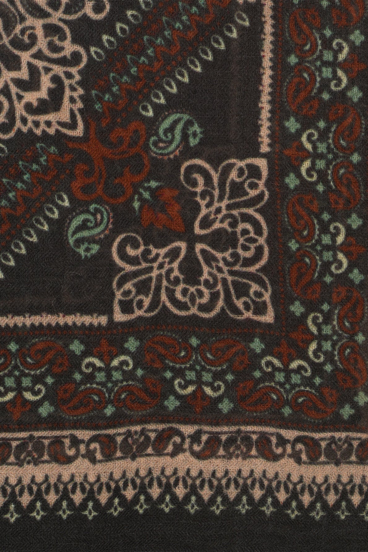 A close-up of a textile with intricate floral and geometric patterns in beige, red, green, and black colors, resembling a traditional imprimé bandana or ornamental rug design. This carré 90x90 is crafted from laine fine, adding an elegant touch to its timeless aesthetic.