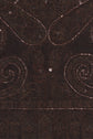 Dark brown fabric with intricate swirling patterns and sequins sewn in curved lines, reflecting light. The richly textured textile features motifs brodés that enhance its decorative appeal, making it suitable for elegant clothing or upholstery.