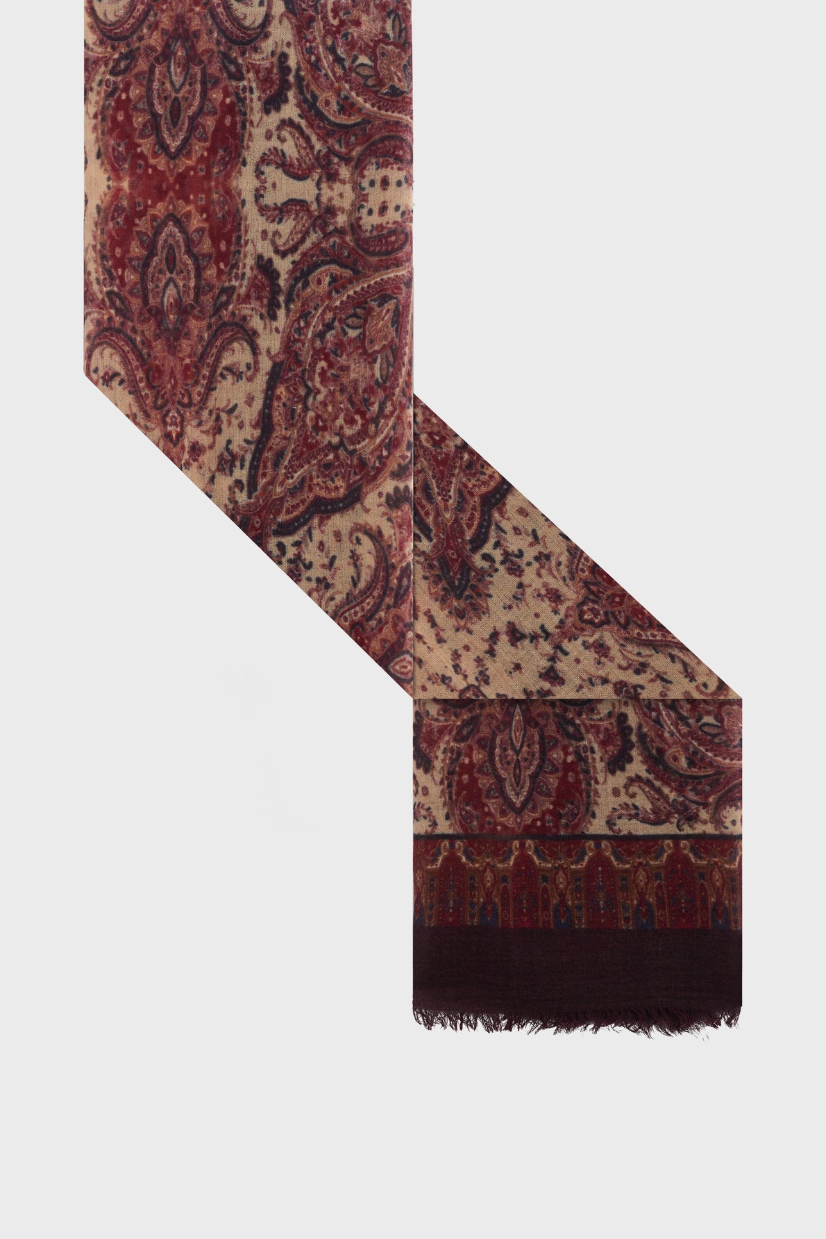 A rectangular scarf with a beige background, red and maroon paisley pattern, and a dark fringed edge, shown on a white backdrop. This elegant écharpe bordeaux combines the softness of laine modal for comfort and style, making it the perfect accessory for any occasion.