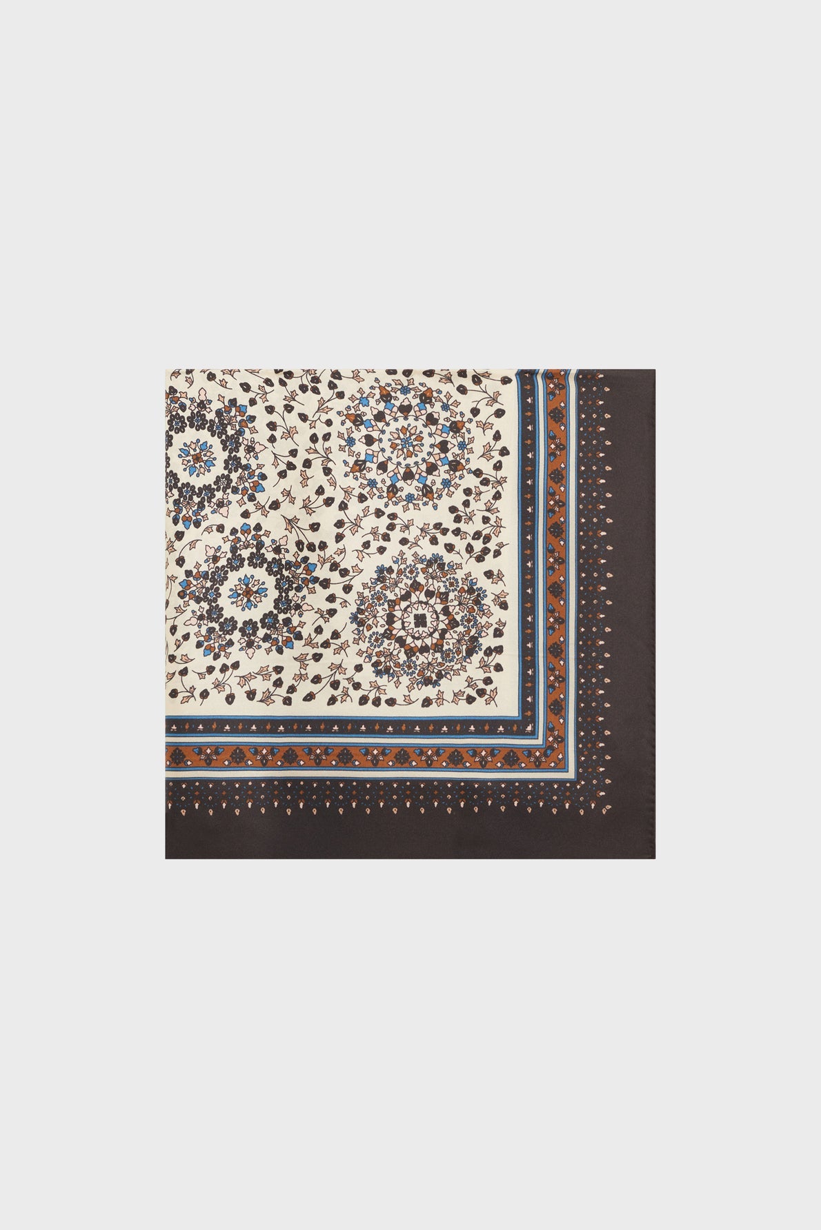 A carré en soie, this square scarf features a cream center adorned with an intricate motif floral in blue, brown, and tan, bordered by elegant blue and brown lines and finished with a brown edge accented by small light-colored dots—perfect for adding a touch of foulard bohème charm to any outfit.