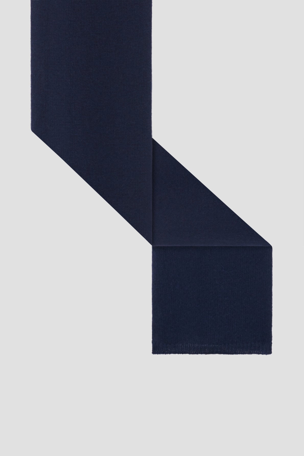 A dark navy blue wool scarf (bleu marine) is displayed on a light gray background, folded in a zigzag manner with clean edges and a soft texture, reminiscent of an elegant écharpe in fine cachemire.