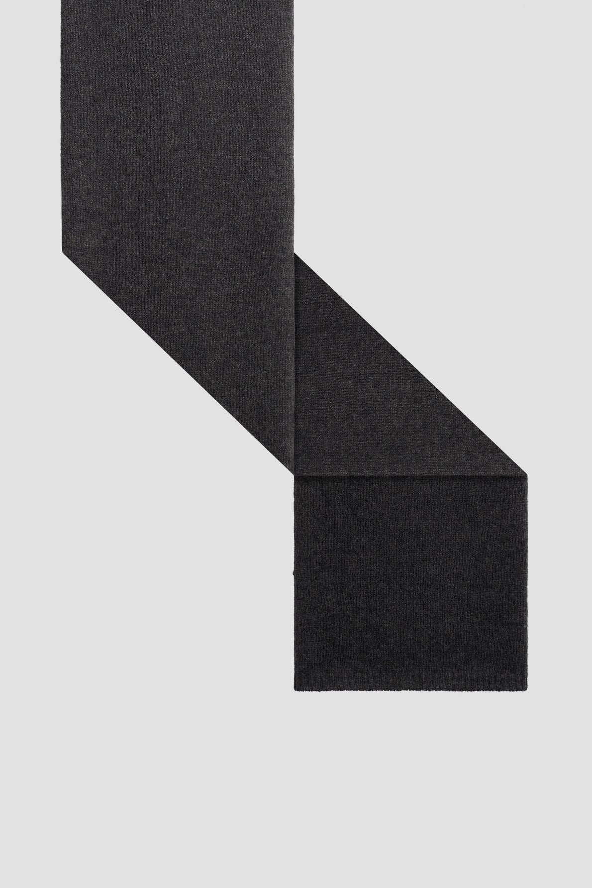 A charcoal gray wool scarf, or écharpe anthracite, is laid flat on a light background, with one end folded over the other at an angle, showing its rectangular shape and soft texture.