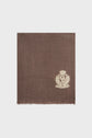 Brown écharpe laine, designed in a square shape with a beige embroidered crest and decorative text in the bottom right corner; the fabric has frayed edges and a soft texture. The background is plain white, adding to the classic écharpe preppy style.
