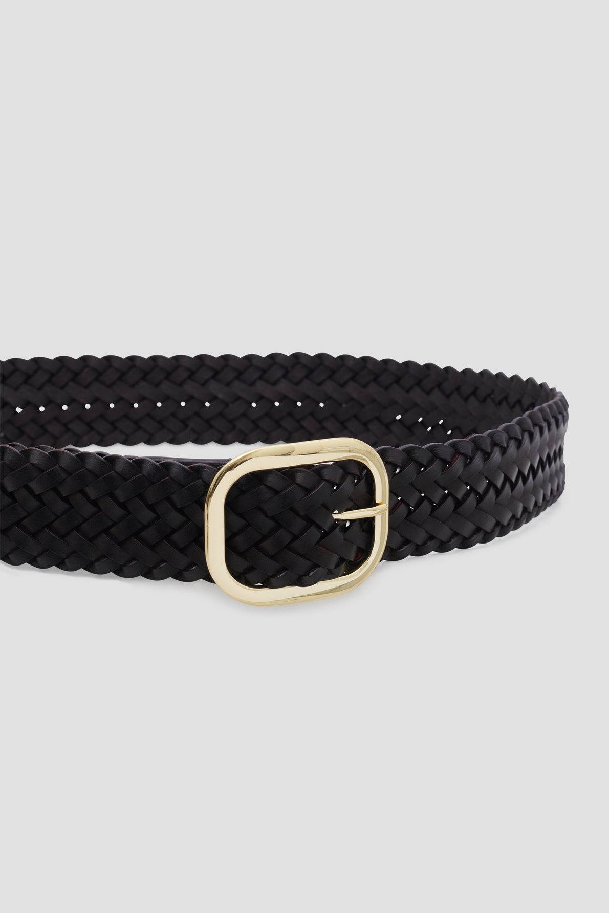 A black ceinture tressée with a rectangular gold buckle is displayed against a plain light gray background.