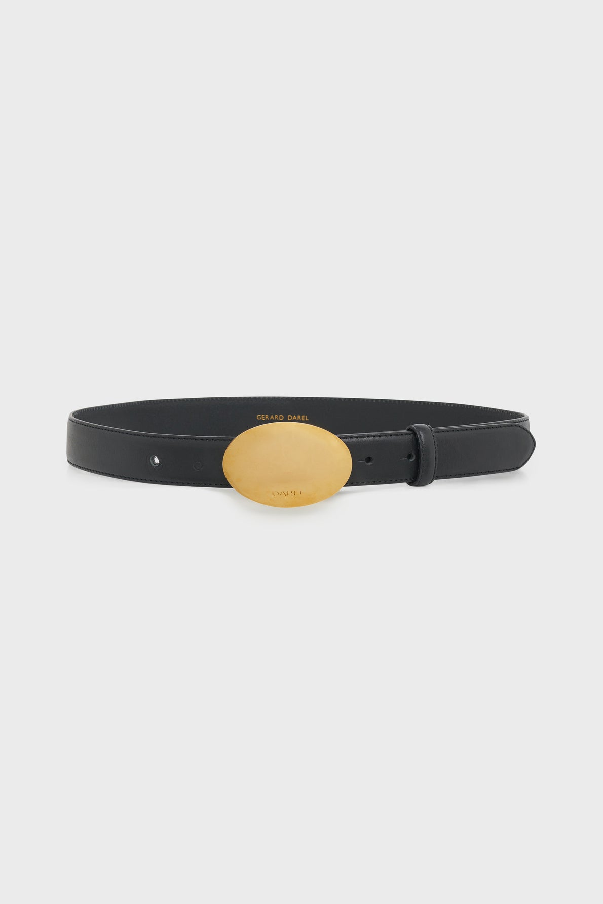 A black leather ceinture élégante with a large, smooth, oval-shaped gold buckle is displayed against a plain white background.