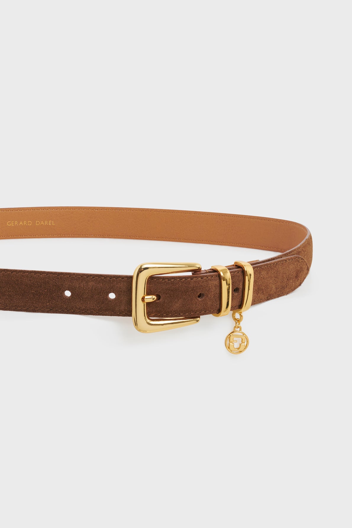 A brown suede leather belt with a gold buckle and a small round gold charm attached, this ceinture élégante by Gerard Darel is displayed on a plain white background.