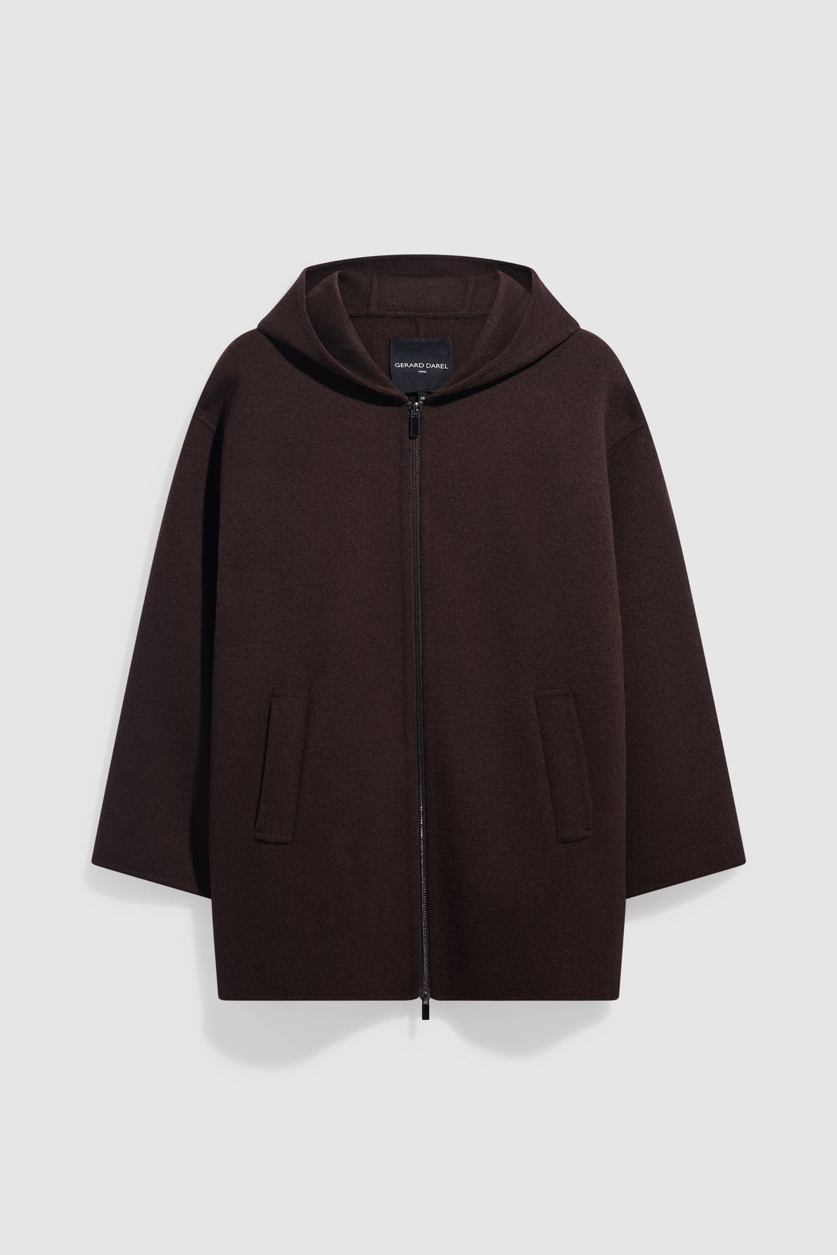 A dark brown, hooded cape-style coat crafted from laine double face, featuring a front zipper and two front pockets, displayed against a plain light background.
