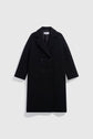 A chic à la française, long, black double-breasted overcoat crafted from luxurious drap de laine, featuring wide lapels and two front flap pockets, displayed against a plain light gray background.