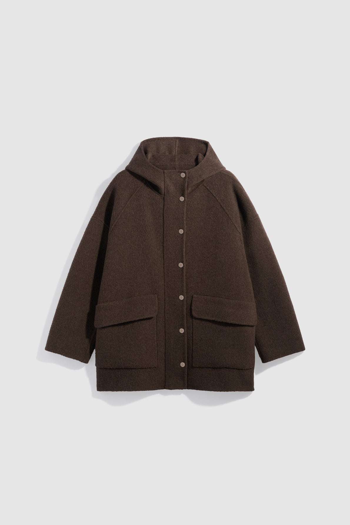 A dark brown manteau capuche with large front pockets and a row of silver snap buttons, laid flat on a light gray background.