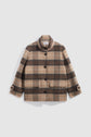 A beige and brown plaid wool jacket, reminiscent of a manteau à carreaux, with black buttons, a collar, two large front pockets, and buttoned cuffs, displayed on a plain white background.