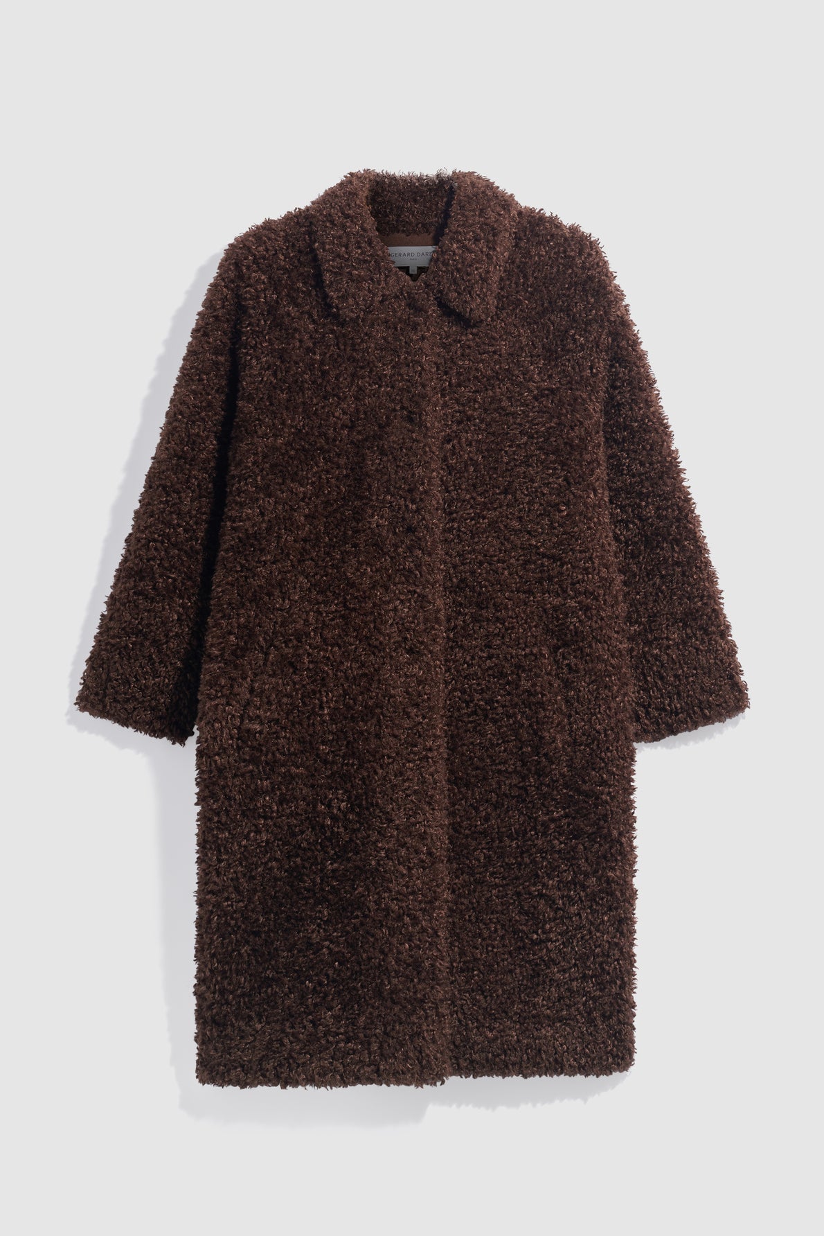 A long, brown, textured tissu bouclé teddy coat with a collar and side pockets, displayed flat on a light gray background.