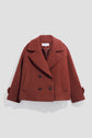 A cropped, double-breasted rust-red pea coat (caban court) with wide lapels, black buttons, and two flap pockets, displayed on a plain light grey background.