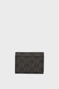 A rectangular portefeuille super plat with a checkered pattern in shades of brown and black, featuring a repeating logo design. The petit portefeuille is positioned upright against a plain light background.