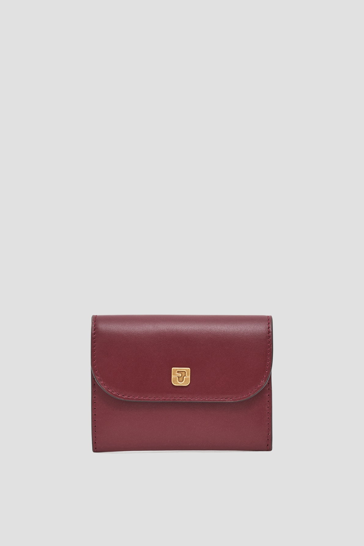 A small, burgundy leather wallet with a gold clasp is centered on a plain light gray background, perfectly embodying the elegance of a portefeuille super plat and the practicality of a petit portefeuille cuir.
