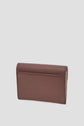 A brown leather wallet is standing upright on a light gray background, showing its smooth back side and neat stitching along the edges—an elegant petit portefeuille cuir designed for those who appreciate both style and practicality.