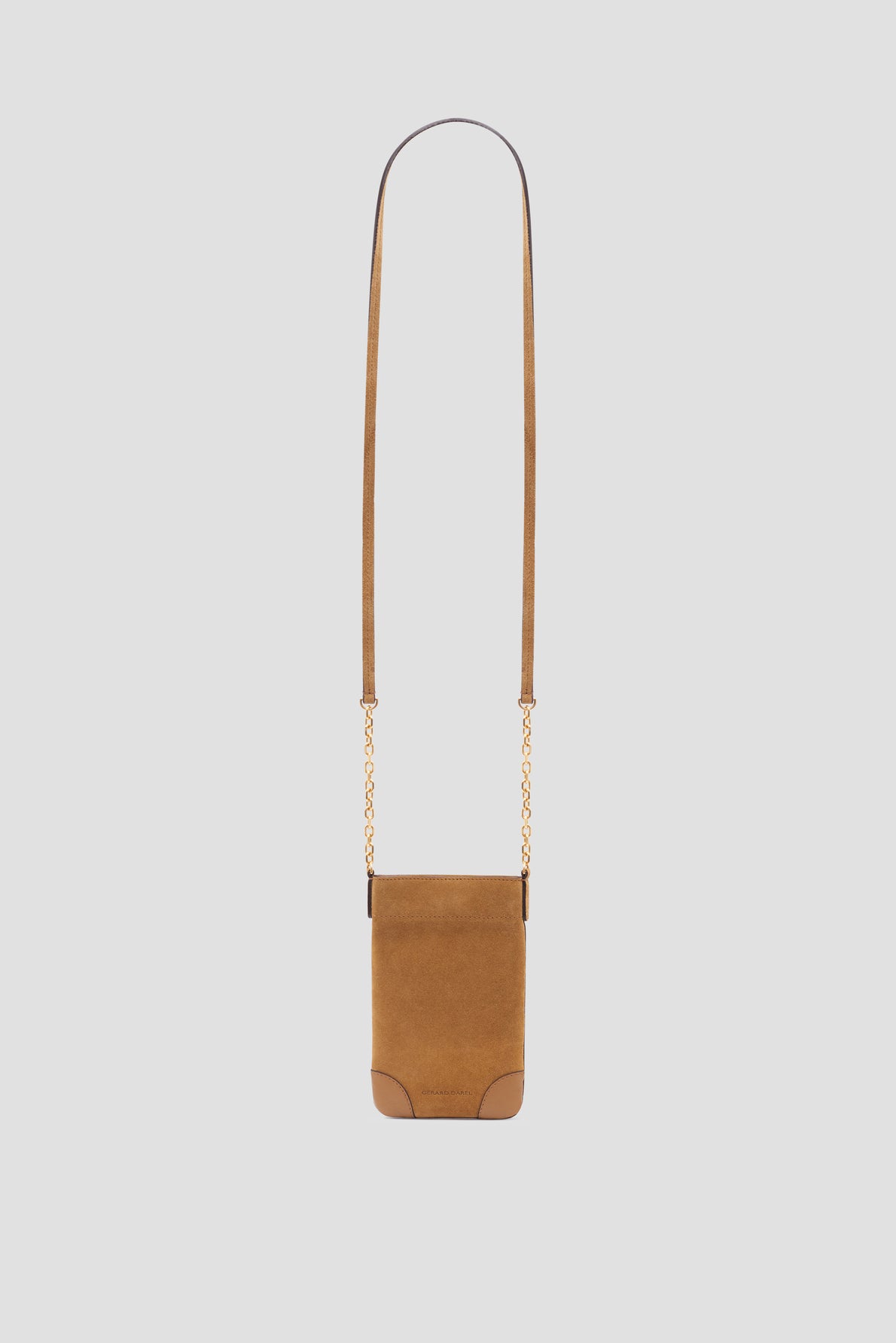 Brown suede crossbody bag with a long thin strap and elegant bandoulière chaîne gold accents on the sides, set against a plain light gray background. The bag is rectangular with rounded corners at the bottom, crafted from soft cuir velours for a luxe finish.