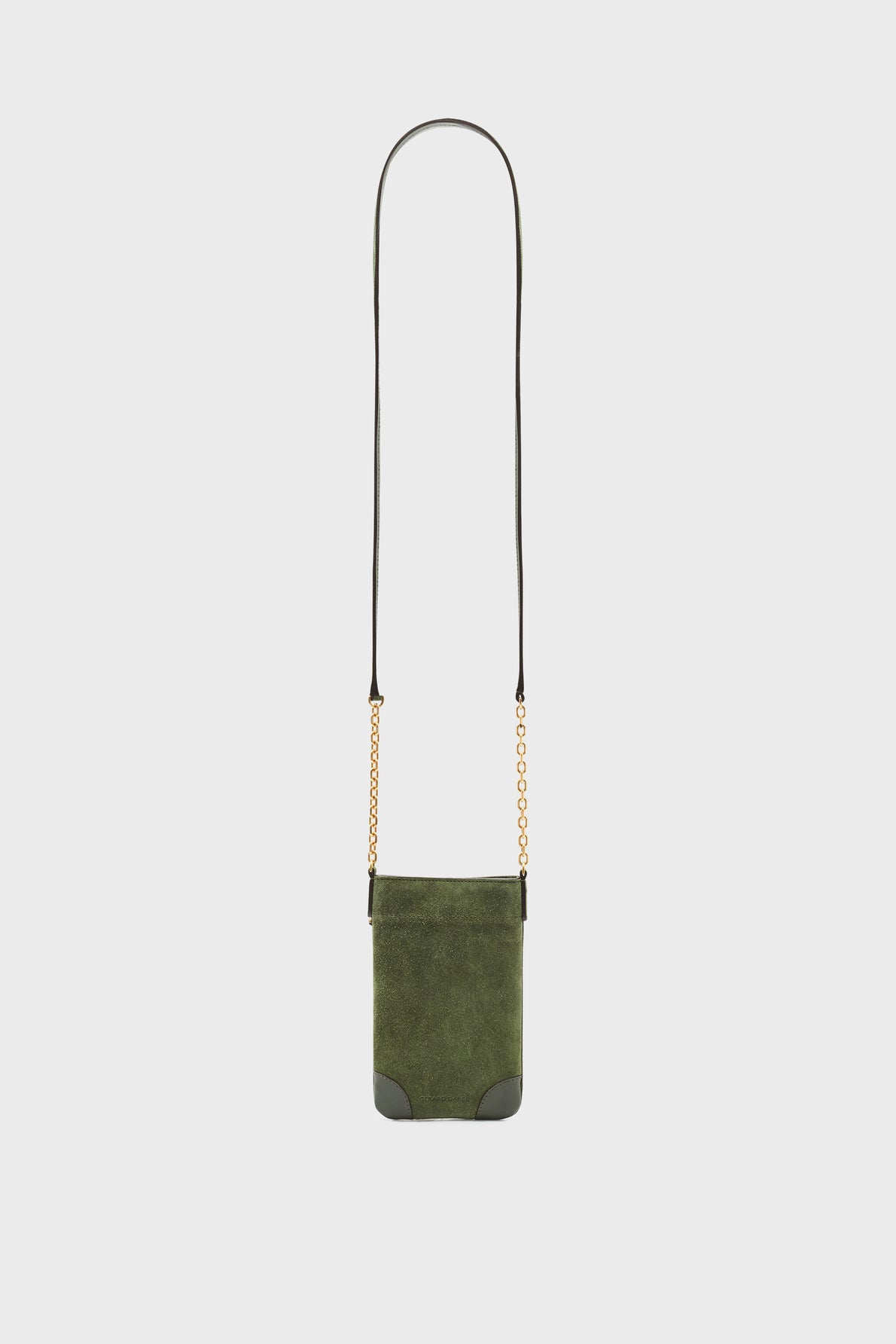 Small green suede crossbody bag crafted from luxurious cuir velours, with black leather corners and a long, thin strap featuring elegant bandoulière chaîne gold accents, displayed against a plain white background.