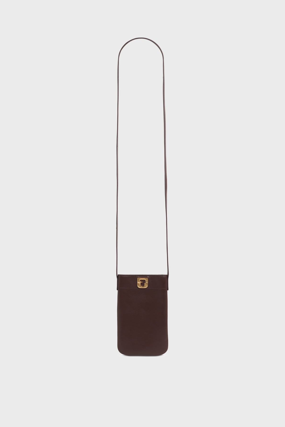 A dark brown cuir de vachette leather crossbody pouch with a long strap and a gold-tone rectangular clasp, displayed on a plain white background—an accessoire tendance perfect for carrying your essentials in style.