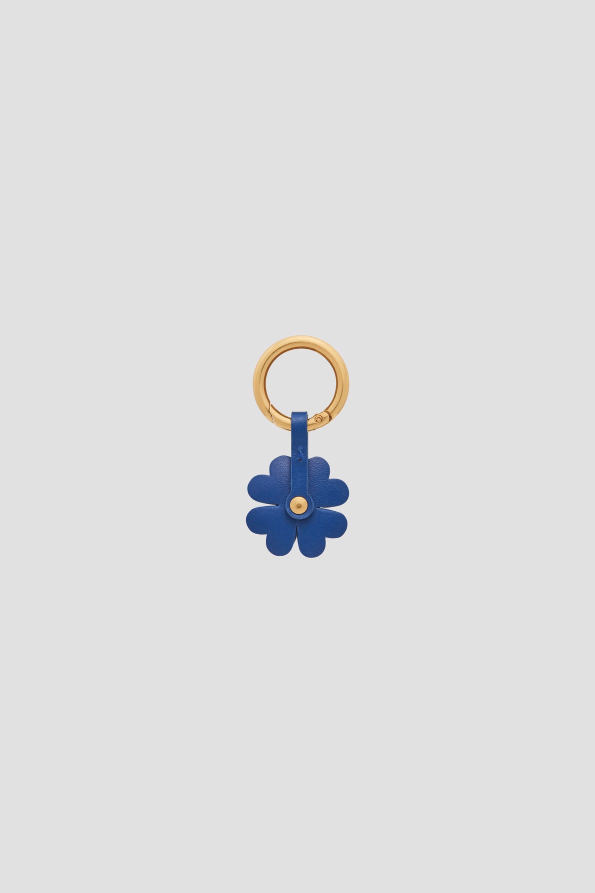 Gold keyring with a blue leather flower-shaped charm en cuir attached, serving as an elegant porte-bonheur and a stylish addition to your accessoires de sac, set against a plain light grey background.
