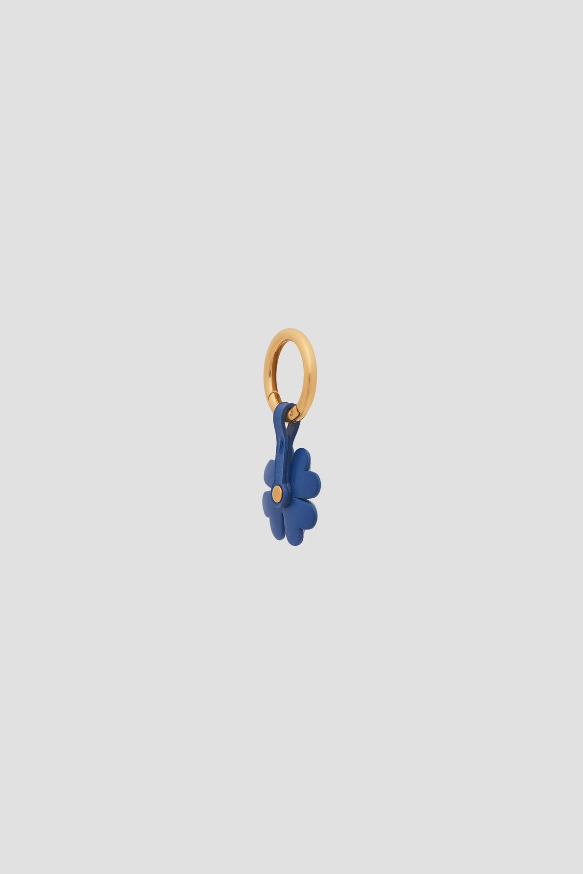 A small gold hoop charm featuring a blue flower-shaped pendant with a gold center, set against a plain light gray background—perfect as an élégant porte-bonheur or to add a unique touch to your accessoires de sac.