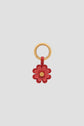 A gold keyring with a red charm en cuir flower, featuring layered petals and a small gold center—a bijou luxe accessory that doubles as a porte-bonheur.